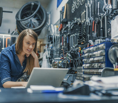 Kvinna i verkstad med laptop - småföretagare