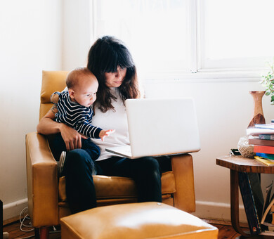kvinna med barn i knäet vid laptop