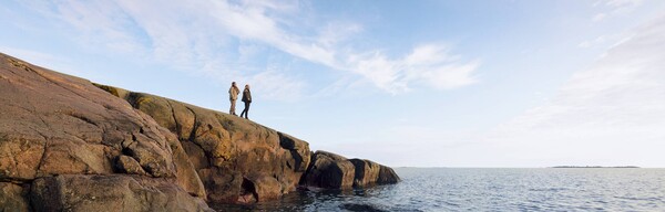 Två personer står på klippa och tittar ut över havet